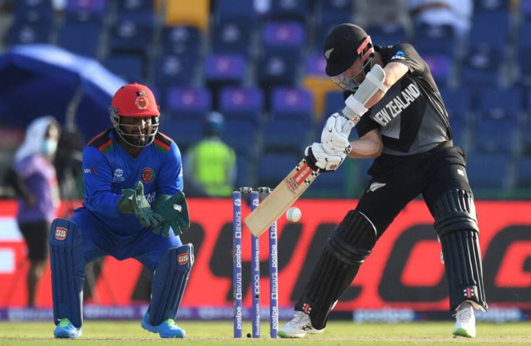 New Zealand's captain Kane Williamson (R) plays a shot as Afghanistan's wicketkeeper Mohammad Shahzad watches during the ICC mens Twenty20 World Cup cricket match between New Zealand and Afghanistan at the Sheikh Zayed Cricket Stadium in Abu Dhabi on November 7, 2021. (Photo by INDRANIL MUKHERJEE / AFP)
