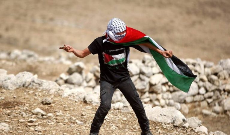 20150917_Palestinian-protestor-wears-flag-and-throws-stones