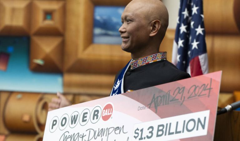 Cheng "Charlie" Saephan holds display check before speaking during a news conference where it was revealed that he was one of the winners of the $1.3 billion Powerball jackpot at the Oregon Lottery headquarters on Monday, April 29, 2024, in Salem, Ore. (AP Photo/Jenny Kane)