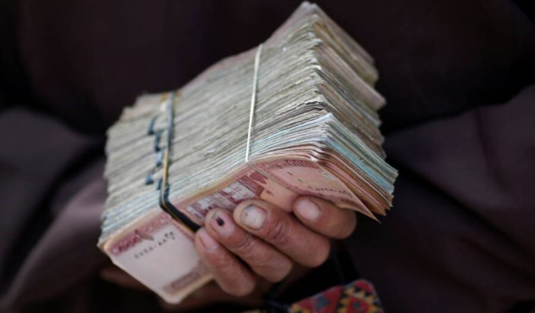 FILE PHOTO: A money changer holds a stack of Afghan currency on a street in central Kabul April 2, 2014. REUTERS/Tim Wimborne/Files
