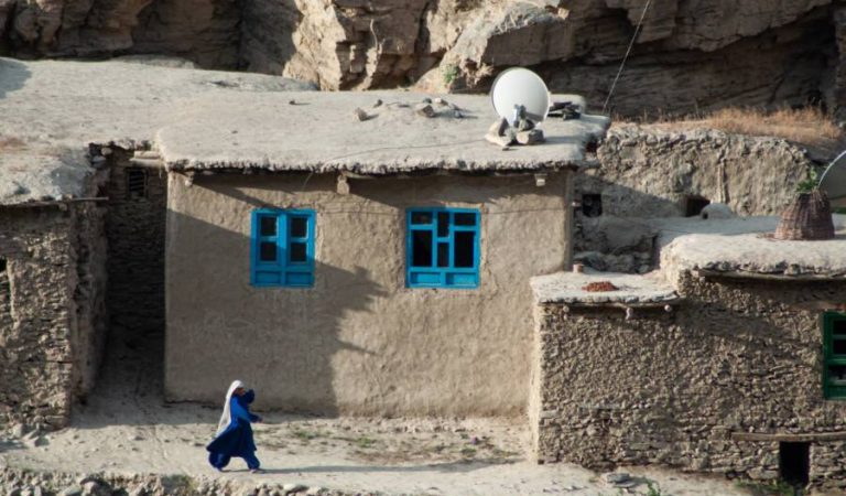 Woman walking in front of houses in Badakhshan, Afghanistan - Joel Heard on Unsplash