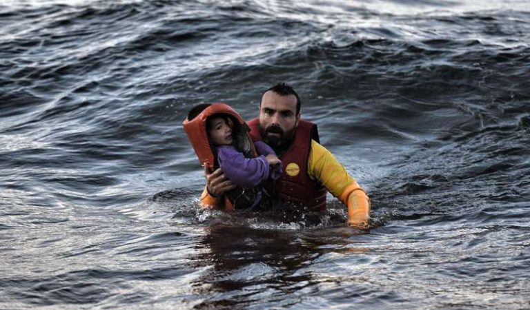A Spanish lifeguard rescues a child as a boat with refugees and migrants sunk on October 30, 2015, while crossing the Aegean sea from Turkey to reach the Greek island of Lesbos. At least 17 children drowned when three boats sank en route from Turkey to Greece, officials said Friday, the latest tragedy to strike migrants braving wintry seas to seek asylum in Europe. Nine adults also lost their lives when the boats went down, with the drownings once again highlighting the human cost as Europe struggles with its worst migrant crisis since World War II. AFP PHOTO / ARIS MESSINIS