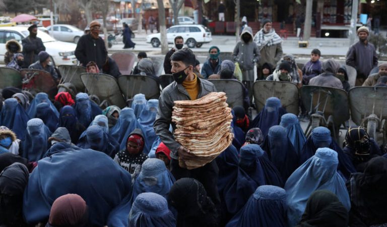 An Afghan boy distributes bread amongst the needy in a crowd at a marketplace in Kabul, Afghanistan, January 31, 2022. REUTERS/Ali Khara