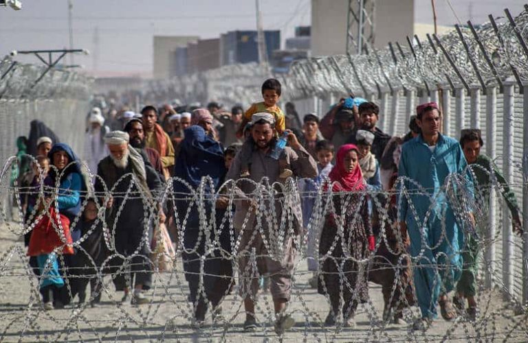TOPSHOT - Afghans walk along fences as they arrive in Pakistan through the Pakistan-Afghanistan border crossing point in Chaman on August 24, 2021 following Taliban's military takeover of Afghanistan. (Photo by - / AFP) (Photo by -/AFP via Getty Images)