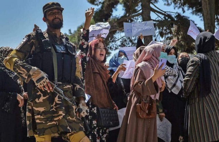 A Taliban fighter stands guard as Afghan women shout slogans during an anti-Pakistan protest rally, near the Pakistan embassy in Kabul on September 7, 2021. - The Taliban on September 7, 2021 fired shots into the air to disperse crowds who had gathered for an anti-Pakistan rally in the capital, the latest protest since the hardline Islamist movement swept to power last month. (Photo by Hoshang Hashimi / AFP) (Photo by HOSHANG HASHIMI/AFP via Getty Images)