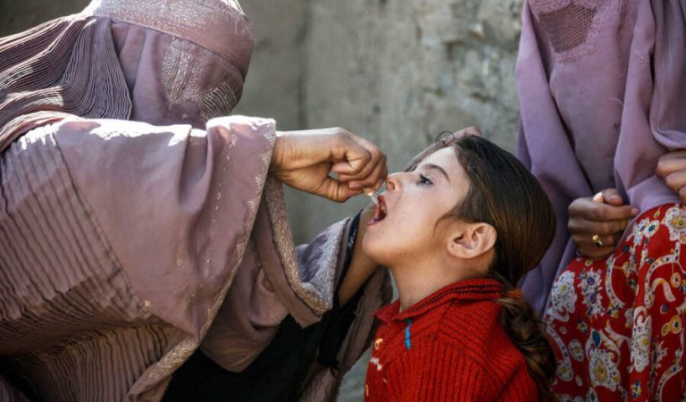 In this photo taken on March 20, 2019, an Afghan health worker administers a polio vaccine to a child in Kandahar province's Arghandab district. - Polio immunisation is compulsory in Afghanistan, but distrust of vaccines is rife, and the programmes are difficult to enforce particularly in rural regions. Militants and religious leaders tell locals that vaccines are a Western conspiracy aiming to sterilise Muslim children, or that such programmes are an elaborate cover for Western or Afghan government spies. (Photo by JAVED TANVEER / AFP) / To go with 'AFGHANISTAN-CONFLICT-VACCINES-POLIO-TALIBAN', FEATURE by Rashid Durrani with Usman Sharifi        (Photo credit should read JAVED TANVEER/AFP via Getty Images)