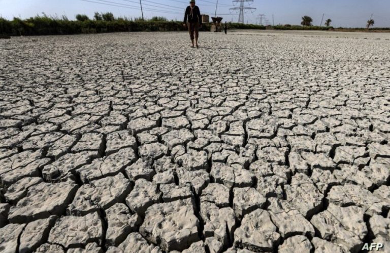 A man walks on cracked mud covering the surface of a dry fish farm in the village of Albu Mustafa in Hilla, about 100 km (62 miles) south of Baghdad on July 6, 2023, following a crack down by the Iraqi government on unauthorised ponds in an effort to meet the country's water demands. Water supply in Iraq, which the United Nations ranks as one of the five countries most impacted by some effects of climate change, is in a dire state. Declining rain over the past four years coupled with rising temperatures has brought water levels in the Tigris and Euphrates rivers to staggering lows, for which Baghdad also accuses upstream dams built by neighbouring Turkey and Iran. (Photo by Ahmad AL-RUBAYE / AFP)