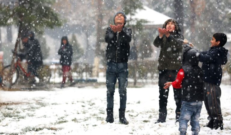 Boys play in a park during snowfall in Kabul on December 29, 2022. (Photo by AFP)