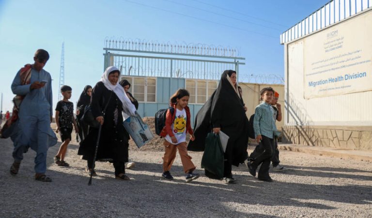 In this photo taken on September 12, 2024, Afghan refugees walk after their deportation from Iran, at a registration centre near the Afghanistan-Iran border in the Islam Qala district of Herat province. - At the border with Iran, streams of Afghan refugees return with children in their arms, their entire worldly possessions contained in a large bag. Every day up to 3,000 Afghans -- some who were born in Iran -- arrive back in their home country after a failed attempt a better life. (Photo by Mohsen KARIMI / AFP) / TO GO WITH 'AFGHANISTAN-IRAN-REFUGEE-RIGHTS, REPORTAGE' BY PASCALE TROUILLAUD AND QUBAD WALI