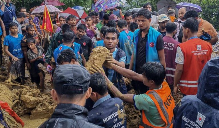 Bangladesh rescue personnel and volunteers work at the site of a landslide triggered by heavy rains at a school in the Kutupalong refugee camp in Cox's Bazar on July 8, 2026. Heavy rain in Bangladesh triggered a landslide at the world's largest refugee camp on July 8, killing seven children and a teacher during a school class and doubling the death toll from rain-related disasters this week. (Photo by AFP)
