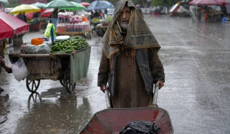 An Afghan laborer pushes a wheelbarrow during a rainy day at the old market in Kabul, Afghanistan, Tuesday, May 3, 2022. (AP Photo/Ebrahim Noroozi)