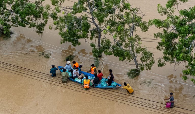 This aerial photo shows people wading through floodwaters in Phan Rang in southern Vietnam's Khanh Hoa province on November 21, 2025. Rescuers raced to find more than a dozen people still missing on November 22 after a week of heavy flooding in Vietnam, where authorities said at least 55 people have died. (Photo by Bao Quan / AFP)