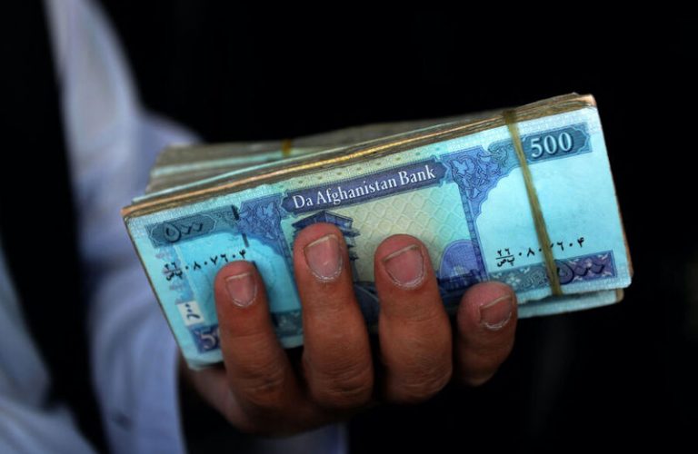A money changer holds Afghani banknotes at a currency exchange market along a road in Kandahar on September 20, 2021. (Photo by JAVED TANVEER / AFP)