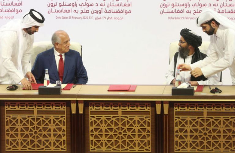 FILE - In this Feb. 29, 2020 file photo, U.S. peace envoy Zalmay Khalilzad, left, and Mullah Abdul Ghani Baradar, the Taliban group's top political leader sign a peace agreement between Taliban and U.S. officials in Doha, Qatar. The Taliban in a statement Sunday, April 5, 2020, said  that a peace deal they signed with the United States is near breaking point accusing Washington of violations that included drone attacks on civilians, while chastising the Afghan government for dithering on the release of 5,000 Taliban prisoners, promised in the agreement. (AP Photo/Hussein Sayed, File)