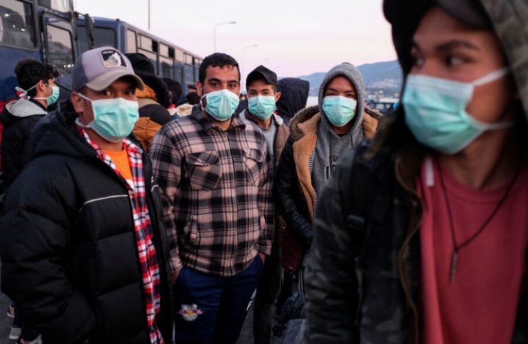 Migrants wearing protective face masks as a precaution against COVID-19 wait to board a ferry to mainland Greece; they were at the port of Mytilene, on the island of Lesbos, March 20, 2020. (CNS photo/Elias Marcou, Reuters) See COVID-REFUGEES-GREECE March 25, 2020.