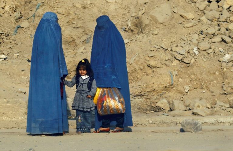 FILE PHOTO: Afghan women clad in burkas wait for transportation on a road in Kabul November 5, 2012. REUTERS/Adnan Abidi