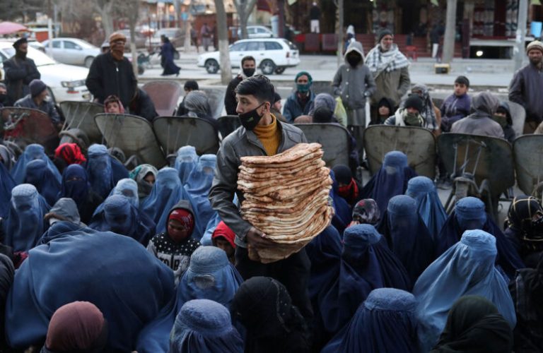An Afghan boy distributes bread amongst the needy in a crowd at a marketplace in Kabul, Afghanistan, January 31, 2022. REUTERS/Ali Khara