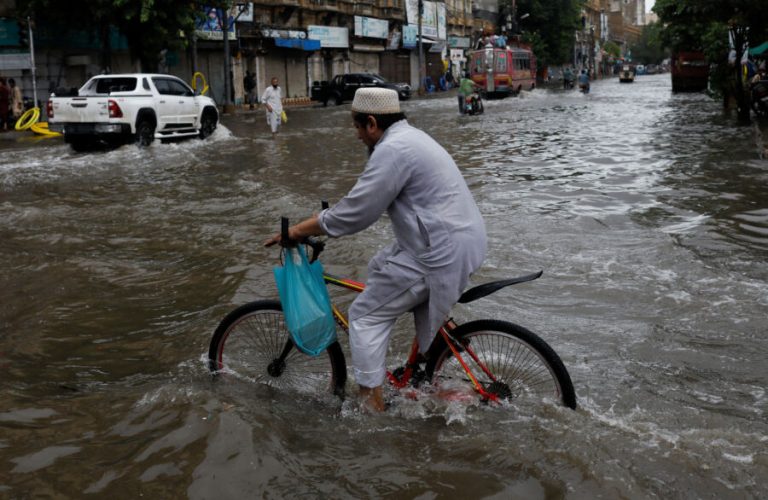 A man rides bicycle along a flooded road, following heavy rains during the monsoon season in Karachi, Pakistan July 25, 2022. REUTERS/Akhtar Soomro