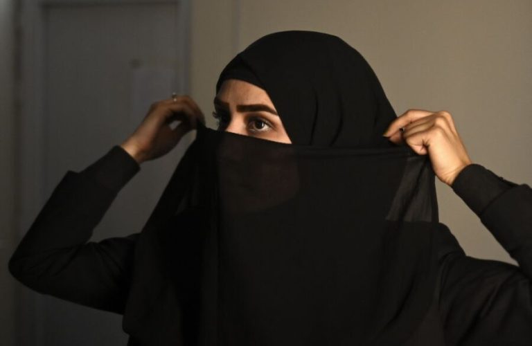 In this photograph taken on May 28, 2022, an Afghan female presenter with news network 1TV, Lima Spesaly prepares to cover her face by a veil before a life broadcast at the 1TV channel station in Kabul. - After initially defying the Taliban order to cover their faces on air, Afghan women television presenters are broadcasting news and other programmes wearing masks. Spesaly, said it was difficult to work like this for hours but vowed to fight for her rights and of other Afghan women that are being increasingly crushed by the hardline Islamist rulers. (Photo by Wakil KOHSAR / AFP)