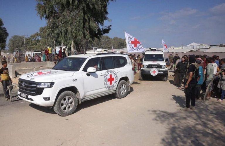 Palestinians gather on both sides of the road as International Red Cross vehicles arrive to transport the second batch of released Israeli hostages, south of Deir al-Balah in the central Gaza Strip on October 13, 2025. The Palestinian militant group has handed over to the REd Cross a second group of 13 Israeli hostages released on October 13. (Photo by Bashar TALEB / AFP) (Photo by BASHAR TALEB/AFP via Getty Images)