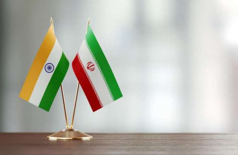 Indian and Iranian flag pair on desk over defocused background. Horizontal composition with copy space and selective focus.