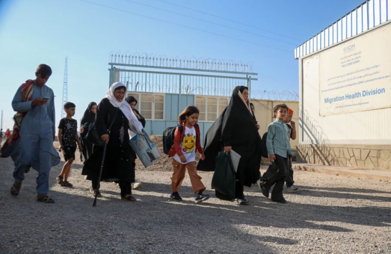 In this photo taken on September 12, 2024, Afghan refugees walk after their deportation from Iran, at a registration centre near the Afghanistan-Iran border in the Islam Qala district of Herat province. - At the border with Iran, streams of Afghan refugees return with children in their arms, their entire worldly possessions contained in a large bag. Every day up to 3,000 Afghans -- some who were born in Iran -- arrive back in their home country after a failed attempt a better life. (Photo by Mohsen KARIMI / AFP) / TO GO WITH 'AFGHANISTAN-IRAN-REFUGEE-RIGHTS, REPORTAGE' BY PASCALE TROUILLAUD AND QUBAD WALI